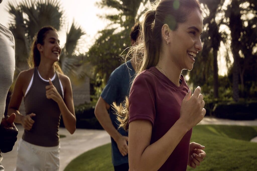 group of people running in the park in the athlon by aldar community